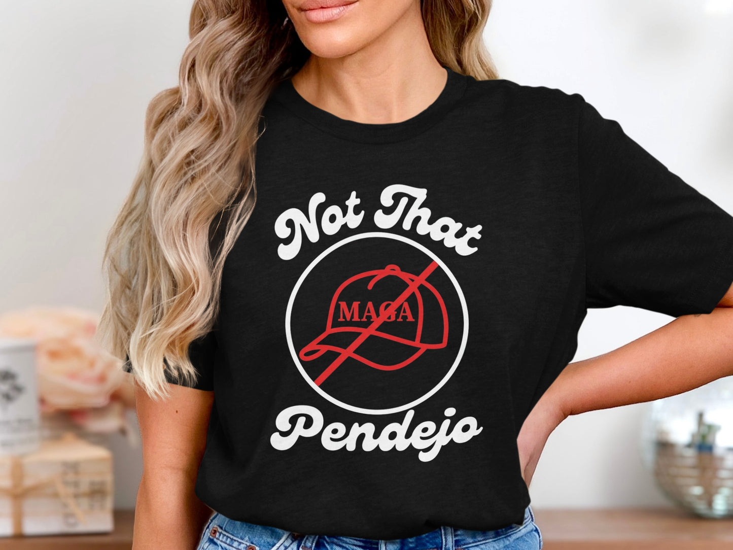 Black t-shirt with white text "Not That Pendejo" and a red circle with a line through a MAGA hat.