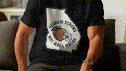 A person wearing a black t-shirt with a graphic design on it, sitting on a couch.