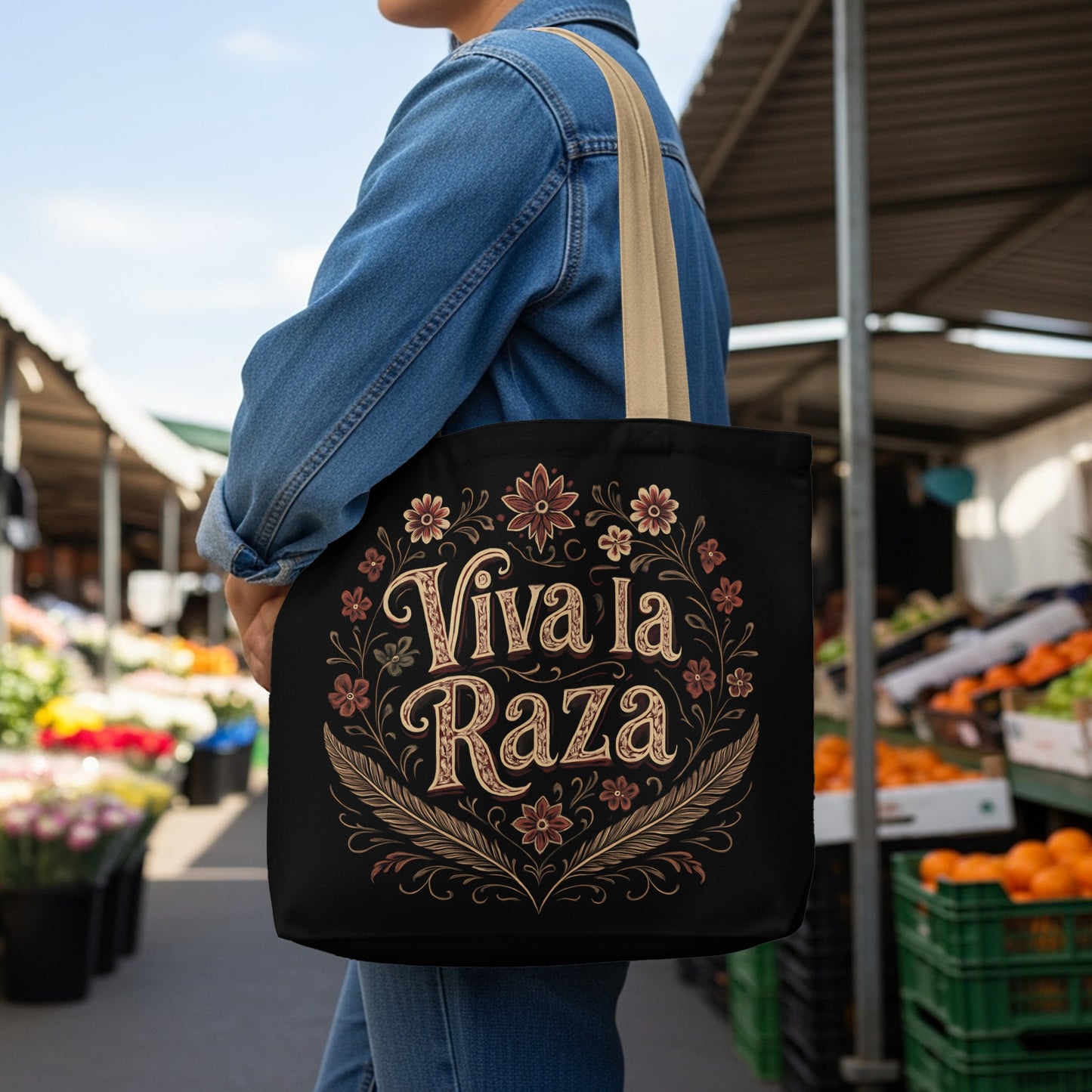Black tote bag with "Viva la Raza" text surrounded by floral and feather designs.