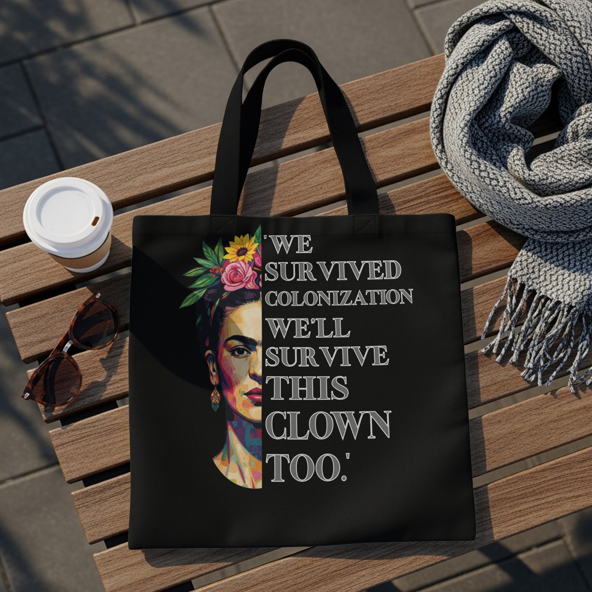 Black tote bag with Frida Kahlo portrait and "We survived colonization we'll survive this clown too" text.