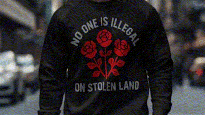 A person wearing a black sweatshirt with a red rose design and text on the back.