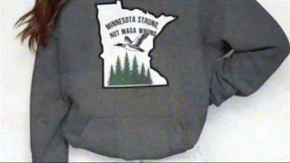 A person wearing a grey sweatshirt with a graphic design on the back.