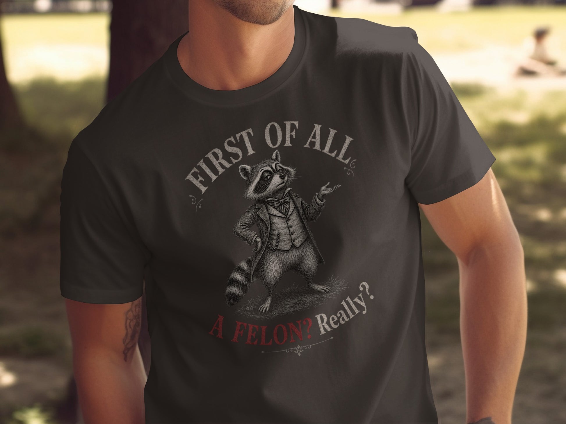 T-shirt with raccoon in a suit saying "First of all, a felon? Really?"