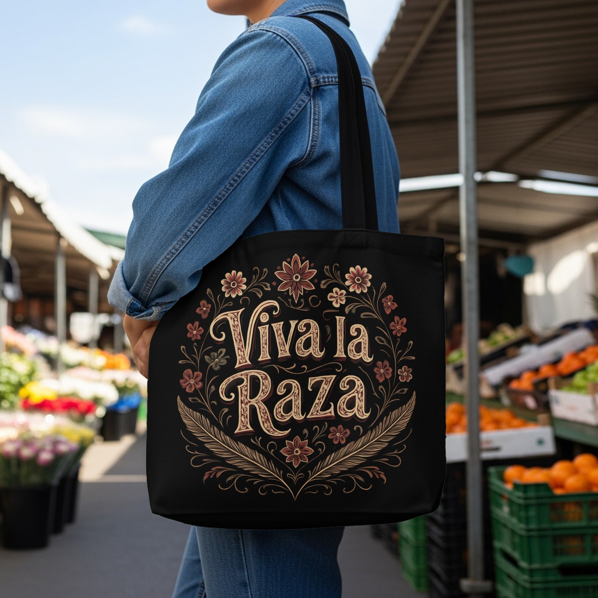 Black tote bag with "Viva la Raza" text and floral border design.