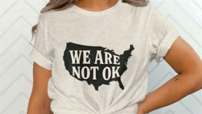 A person wearing a white t-shirt with the text "WE ARE NOT OK" printed on it.