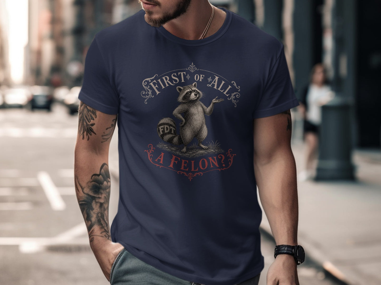 Navy t-shirt with raccoon graphic and "First of All, A Felon?" text.