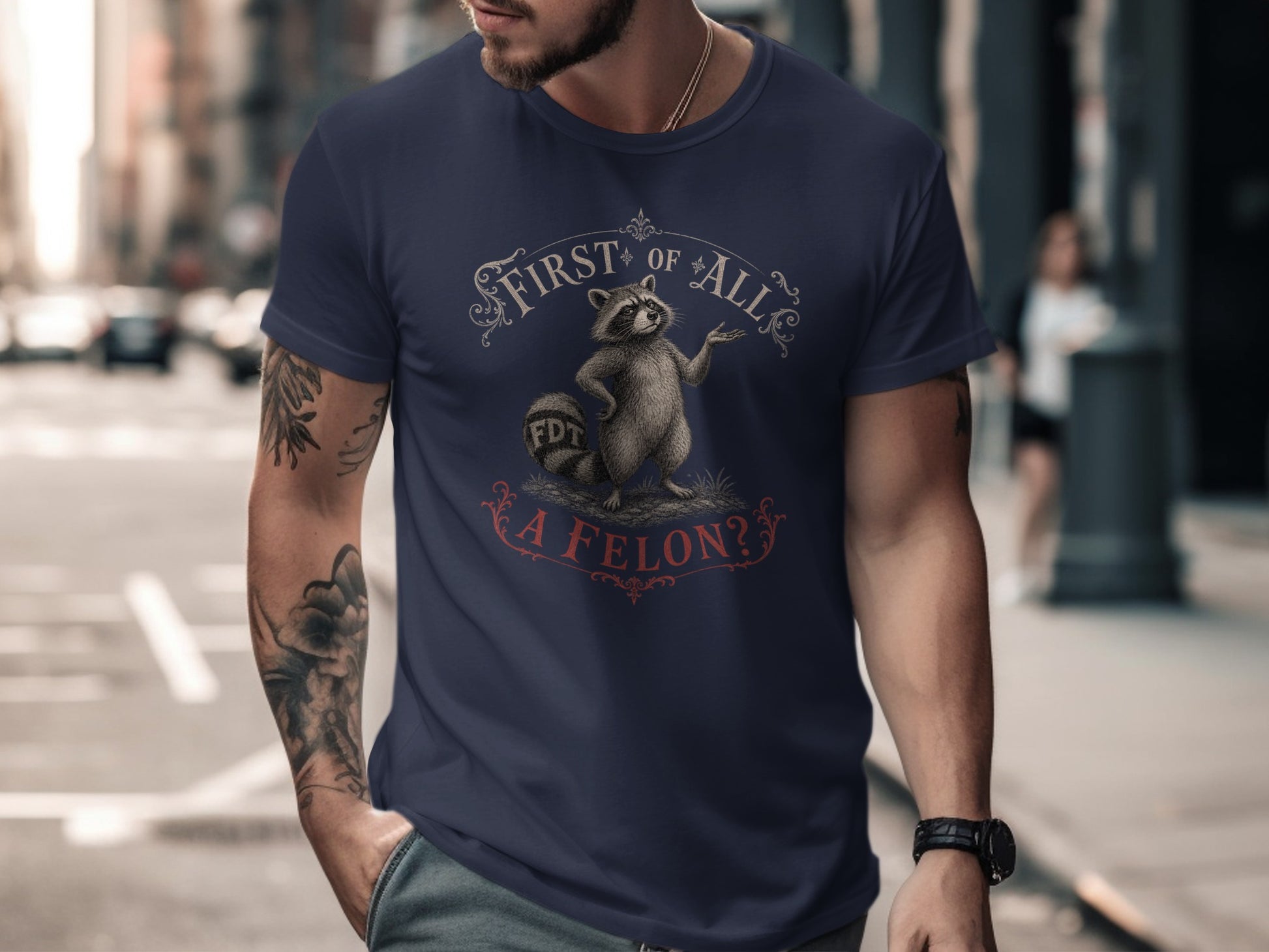 Navy t-shirt with raccoon graphic and "First of All, A Felon?" text.
