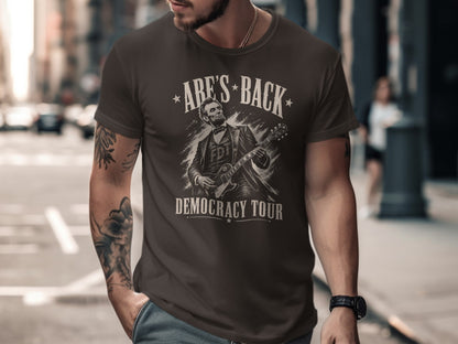 Abraham Lincoln playing guitar graphic on a dark brown t-shirt.