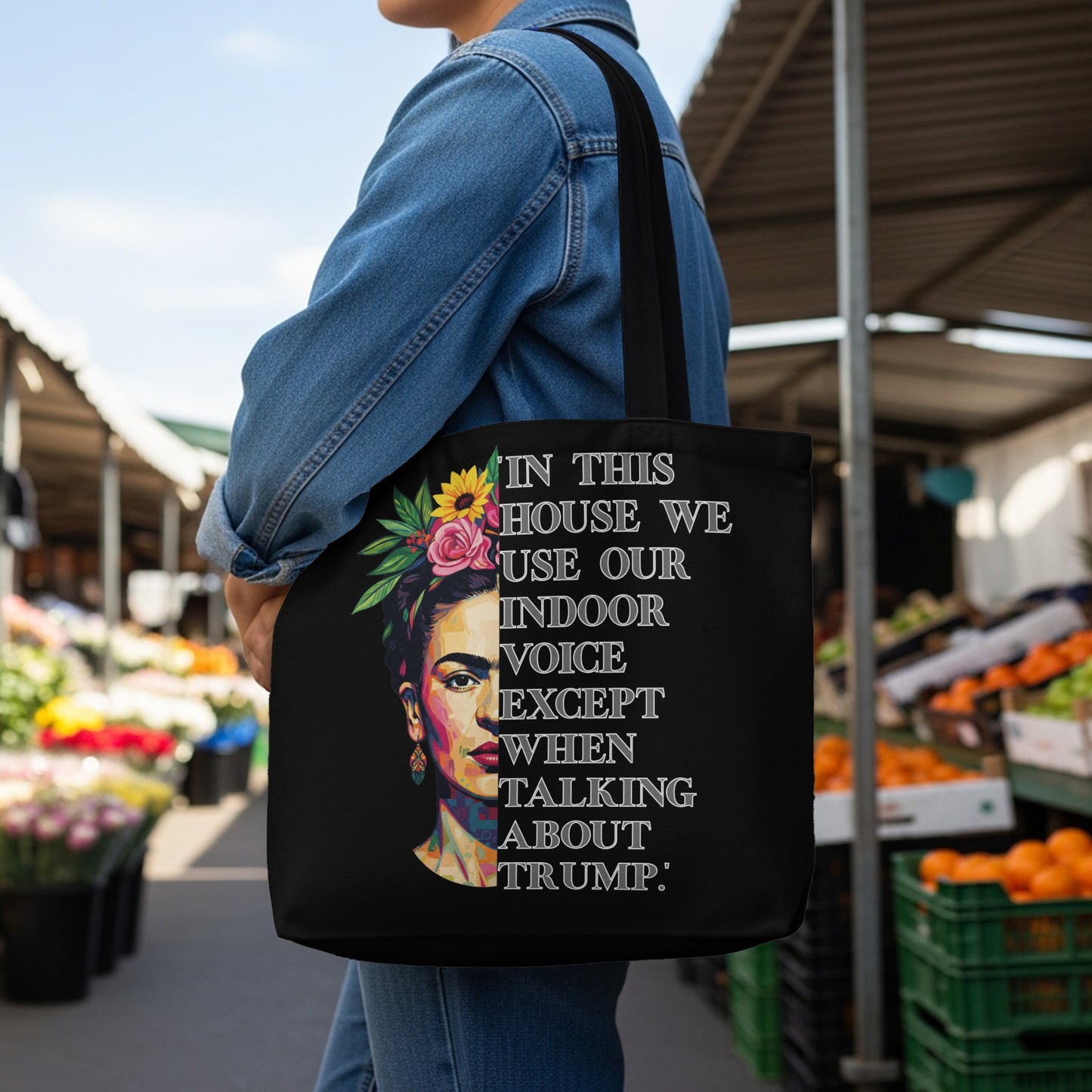 Black tote bag with Frida Kahlo art and "In this house we use our indoor voice except when talking about Trump" text.