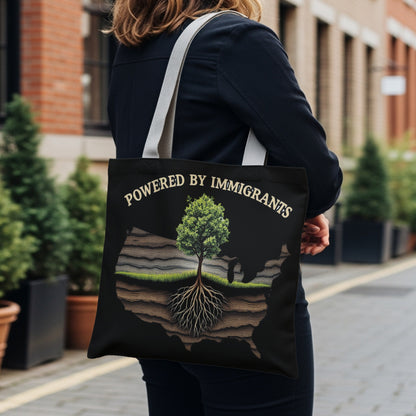 Black tote bag with "Powered by Immigrants" text and a tree growing from a cross-section of land within a US map outline.