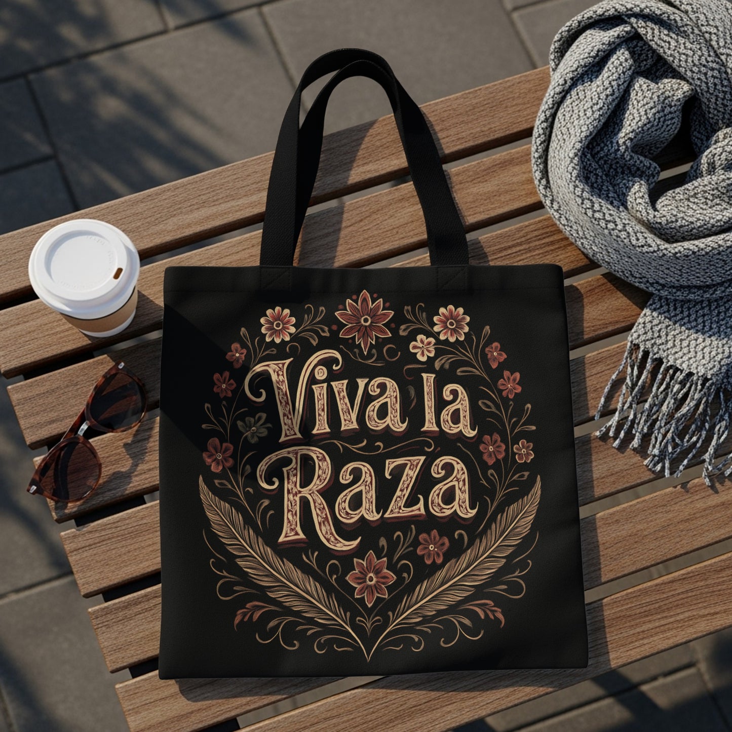 Black tote bag with "Viva la Raza" text and floral border.