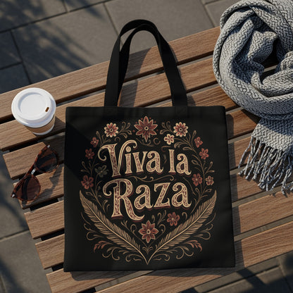 Black tote bag with "Viva la Raza" text and floral border.