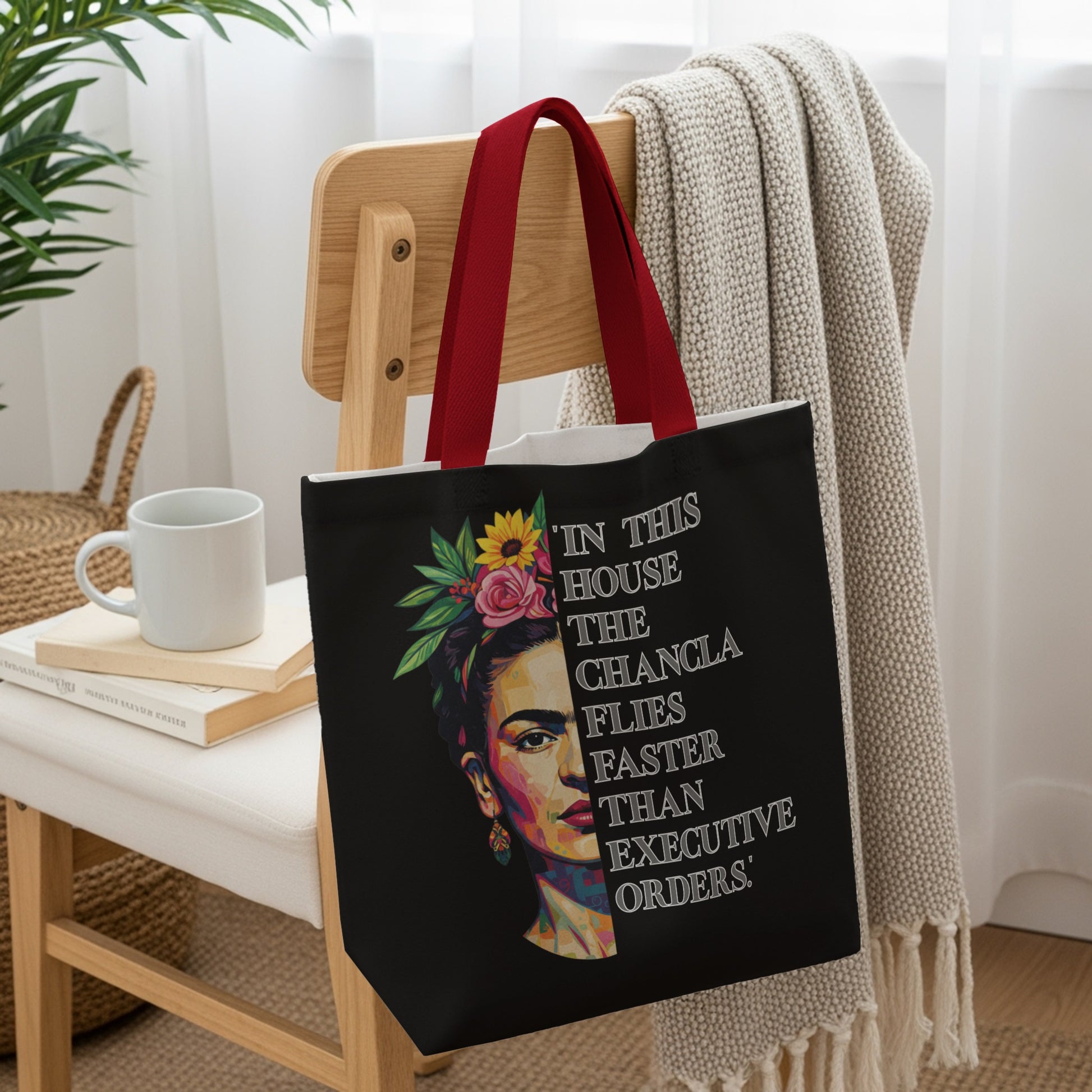 Black tote bag with Frida Kahlo portrait and text, "In this house the chancla flies faster than executive orders."
