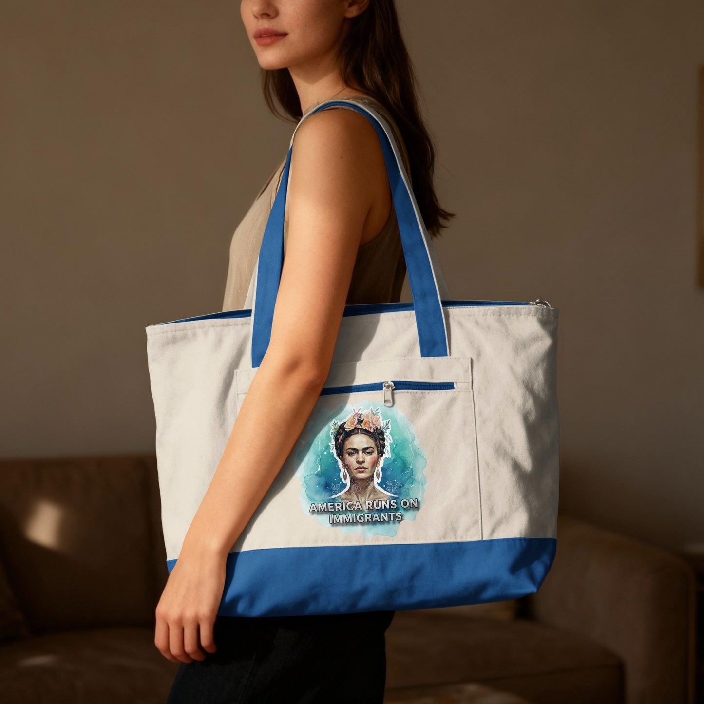 Woman wearing a sleeveless shirt holds a white canvas tote bag with Frida Kahlo art.