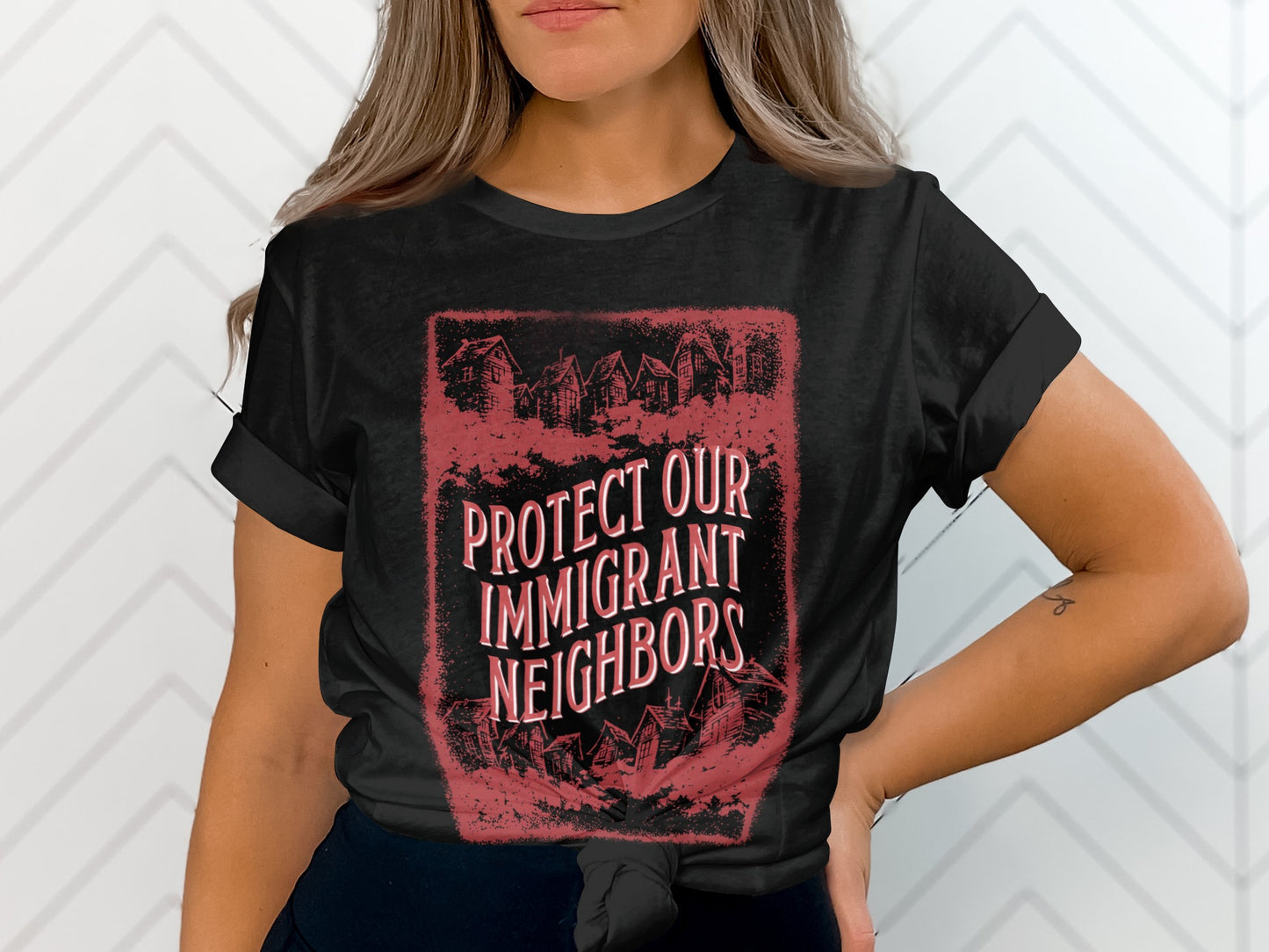 Black t-shirt with "PROTECT OUR IMMIGRANT NEIGHBORS" text and house silhouettes.