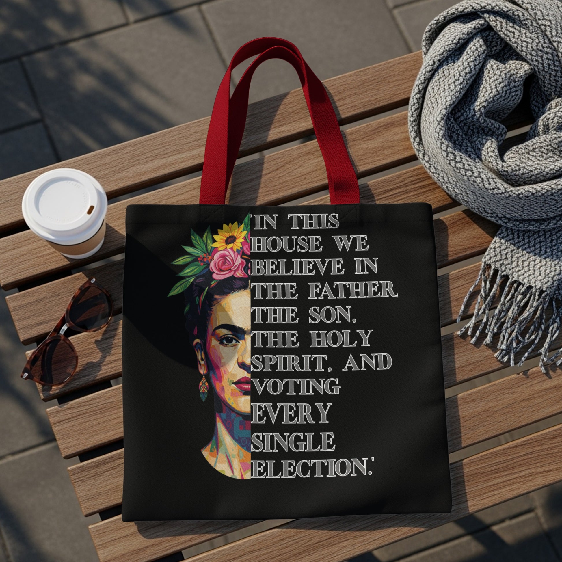 Black tote bag with Frida Kahlo graphic and "In this house we believe in the Father, the Son, the Holy Spirit, and voting every single election."