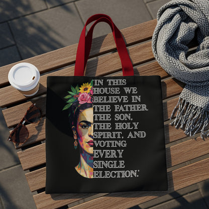 Black tote bag with Frida Kahlo graphic and "In this house we believe in the Father, the Son, the Holy Spirit, and voting every single election."