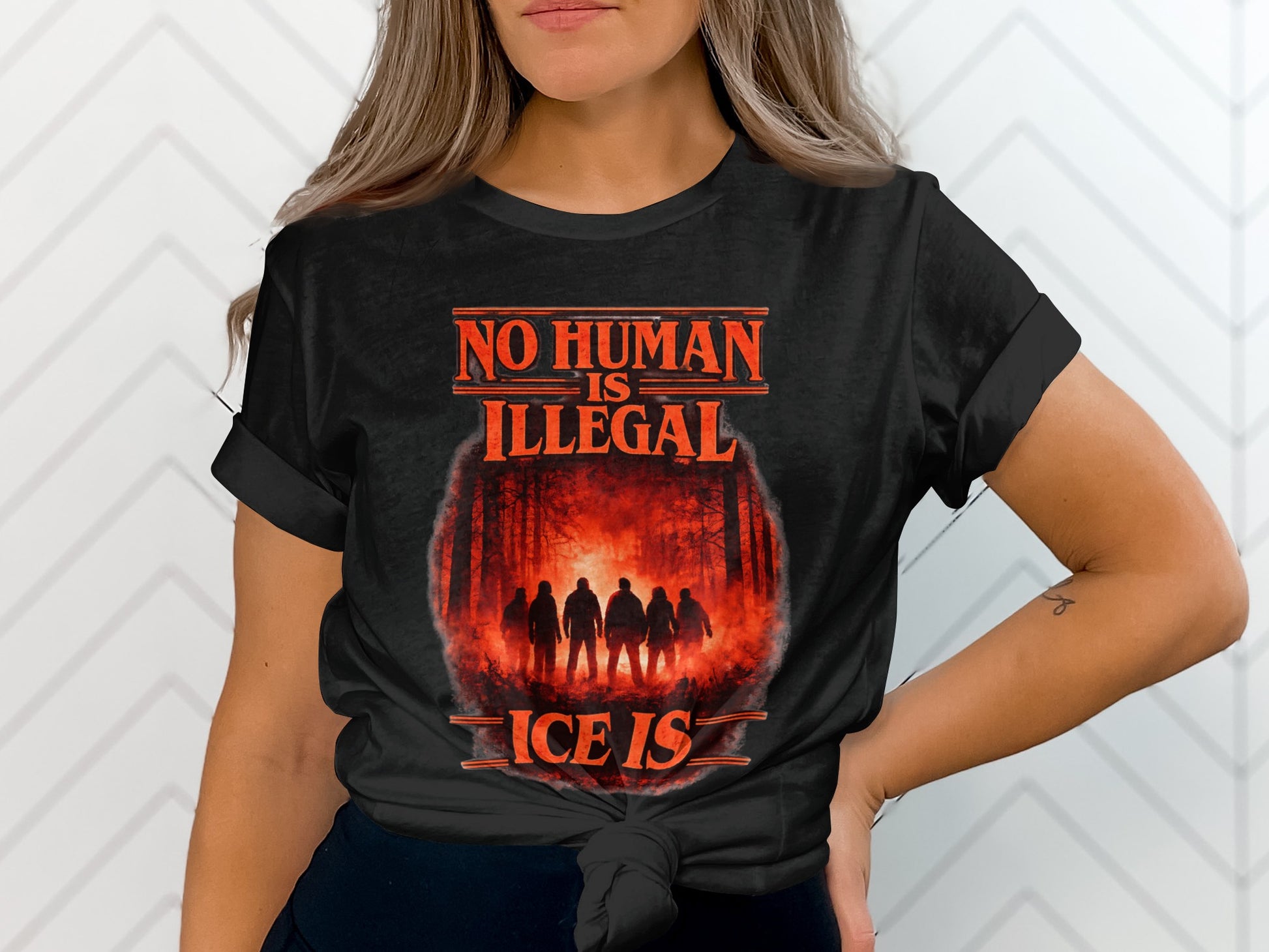 Black t-shirt with "NO HUMAN IS ILLEGAL" and forest silhouette.