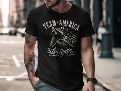 Black t-shirt with raccoon holding American flag and "TEAM AMERICA FDT reluctantly" text.