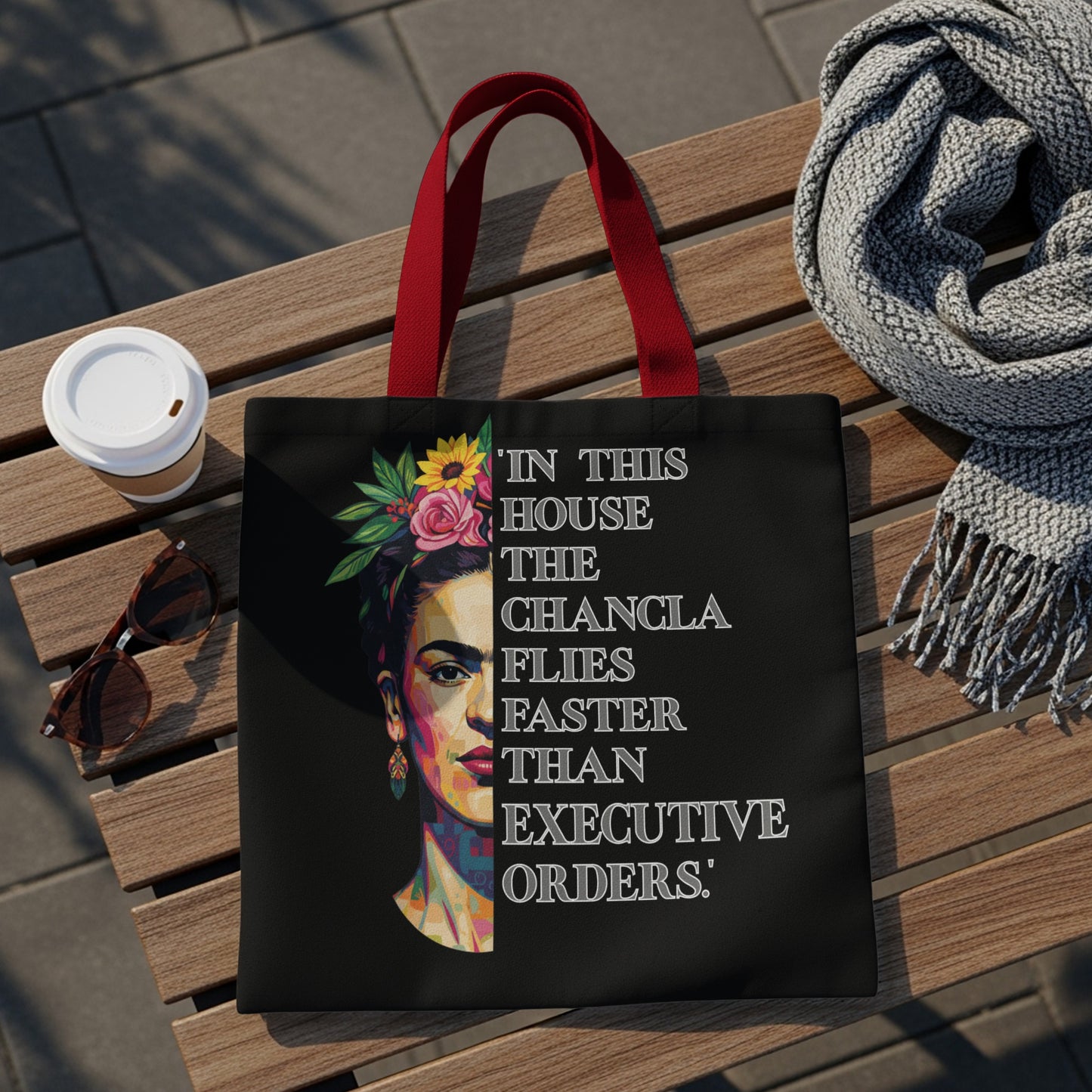 Black tote bag with Frida Kahlo portrait and quote "In this house the chancla flies faster than executive orders."