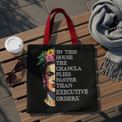 Black tote bag with Frida Kahlo portrait and quote "In this house the chancla flies faster than executive orders."