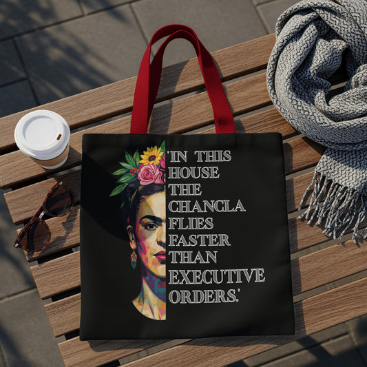 Black tote bag with Frida Kahlo portrait and quote "In this house the chancla flies faster than executive orders."