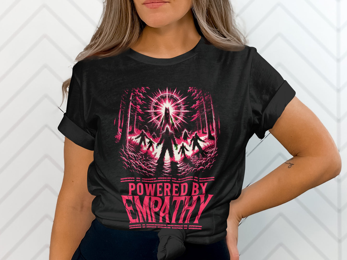 Black t-shirt with pink graphic of figures in a forest and "POWERED BY EMPATHY" text.
