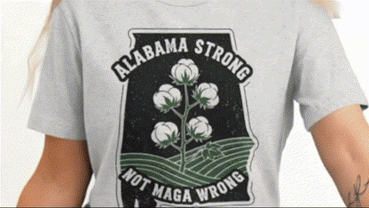 A person wearing a grey t-shirt with a graphic design featuring a cotton plant and the text "ALABAMA STONG NOT MAGA WRONG".