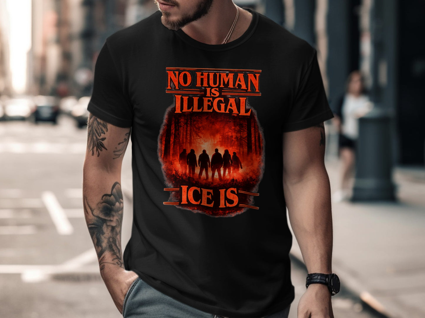 Black t-shirt with "NO HUMAN IS ILLEGAL" text and a forest silhouette.