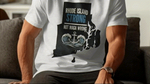 A man wearing a white t-shirt with a graphic design on it, sitting on a couch.