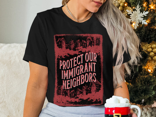 Black t-shirt with "Protect Our Immigrant Neighbors" text and silhouette houses.