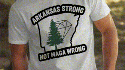 A white t-shirt with a graphic design on the back, featuring a green pine tree and the text "ARKANSAS STRONG NOT MAGA WRONG".