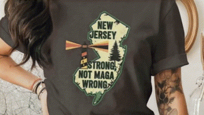 A person wearing a black t-shirt with a graphic design of the state of New Jersey and the text "New Jersey Strong, Not Maga Wrong" printed on it.