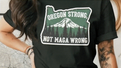 A person wearing a black t-shirt with a graphic design that says "Oregon Strong Not MAGA WRONG".