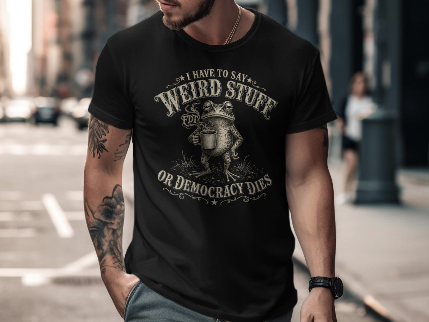 Black t-shirt with text "I have to say weird stuff or democracy dies" and a frog.