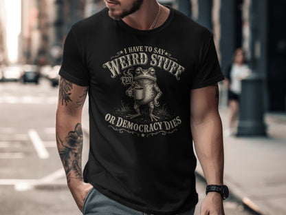 Black t-shirt with text "I have to say weird stuff or democracy dies" and a frog.