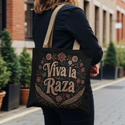 Black tote bag with "Viva la Raza" text and floral border.