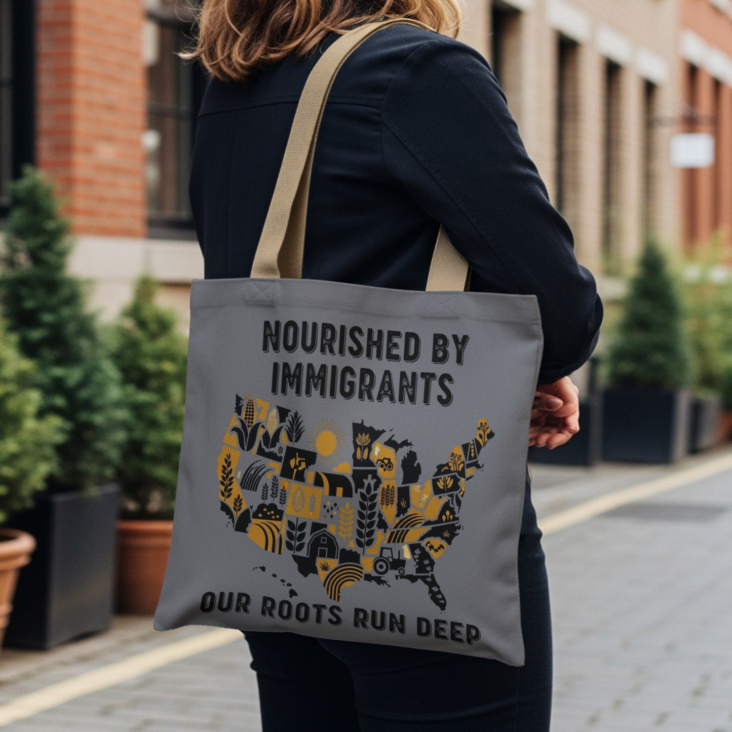 Tote bag with USA map design featuring farm elements and text "Nourished by Immigrants Our Roots Run Deep".