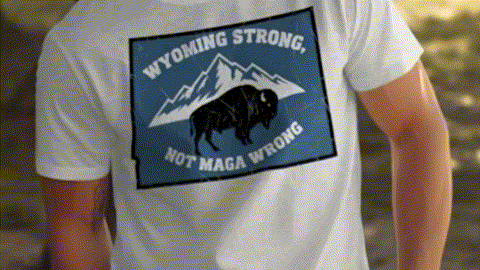 A person wearing a white t-shirt with a graphic design featuring a buffalo and the text "Wyoming Strong Not MAGA Wrong".