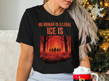Black t-shirt with "NO HUMAN IS ILLEGAL ICE IS" text and silhouette of people in forest.