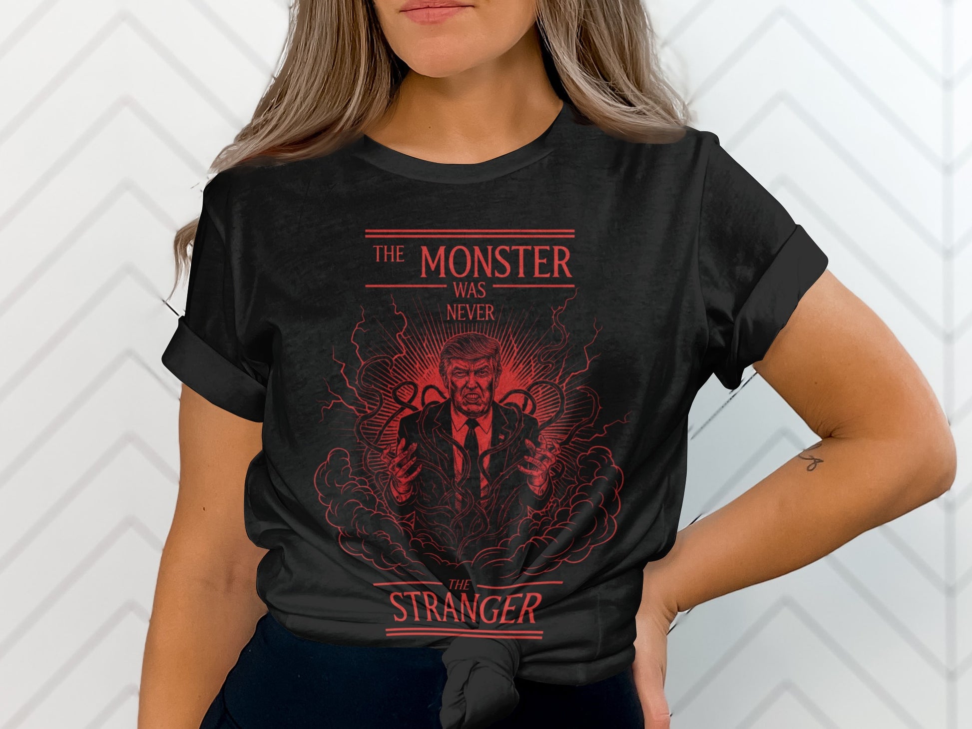 Black t-shirt with "The Monster Was Never The Stranger" text and illustration of Donald Trump.