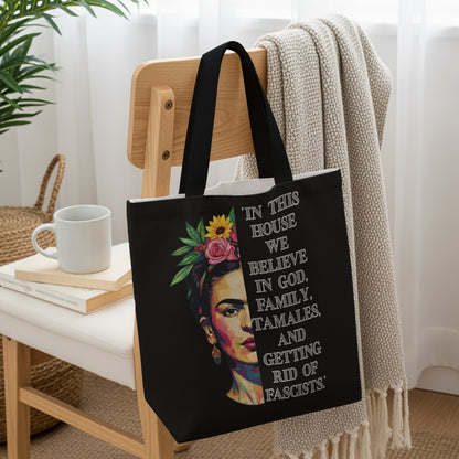Black tote bag with Frida Kahlo portrait and text "In this house we believe in God, family, tamales, and getting rid of fascists."
