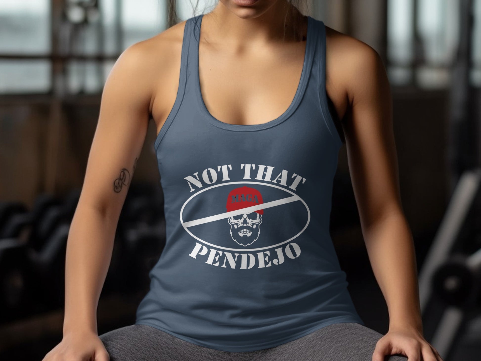 Woman wearing a navy tank top with "NOT THAT PENDEJO" text and a skull logo.