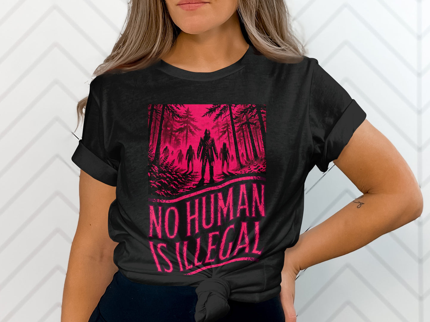 Black t-shirt with "NO HUMAN IS ILLEGAL" text and forest monster illustration.