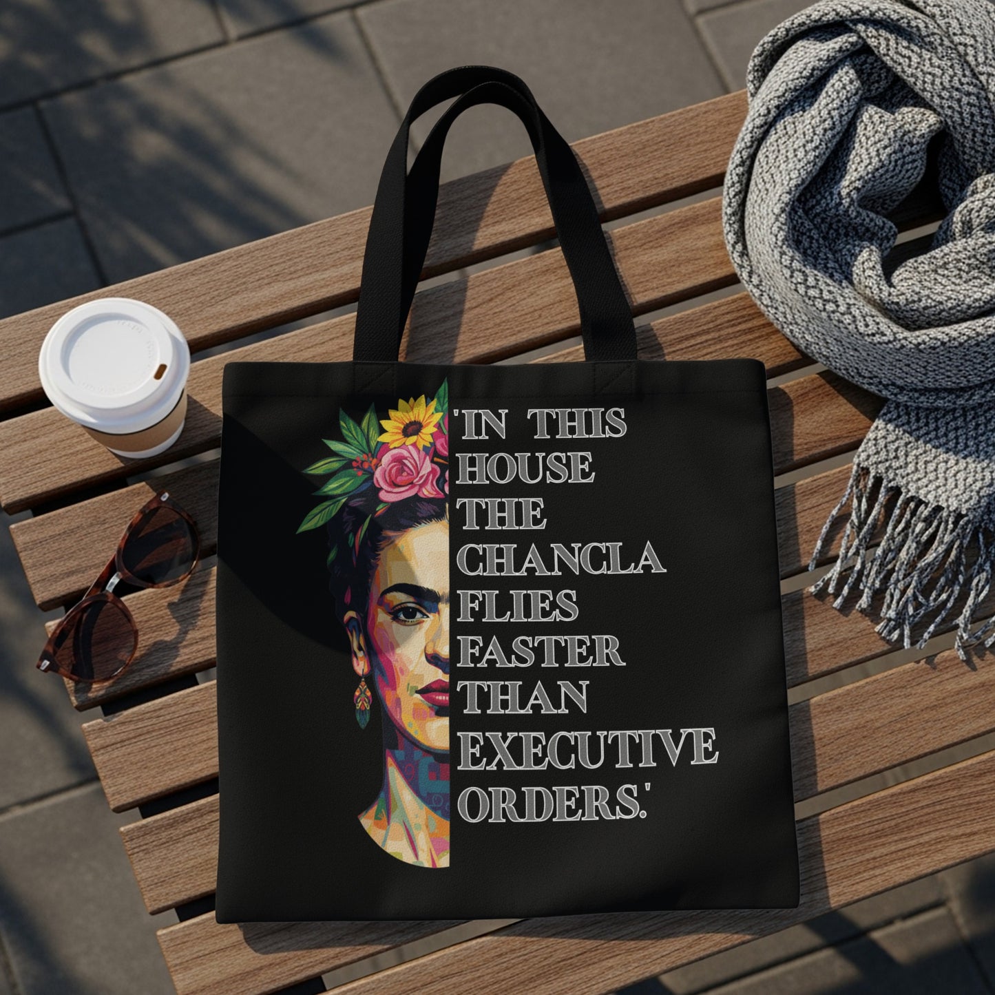 Black tote bag with Frida Kahlo portrait and quote "In this house the changla flies faster than executive orders."