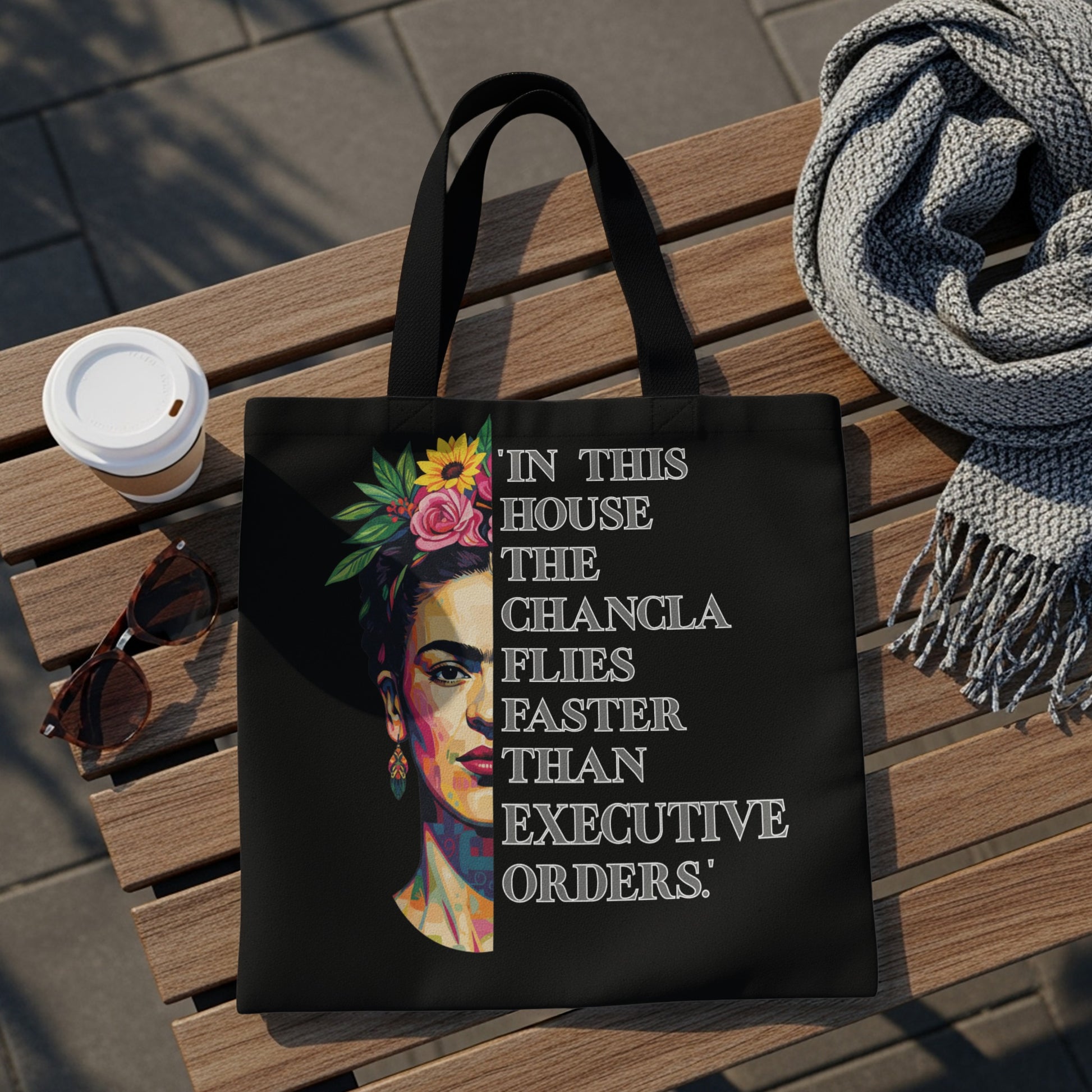 Black tote bag with Frida Kahlo portrait and quote "In this house the changla flies faster than executive orders."