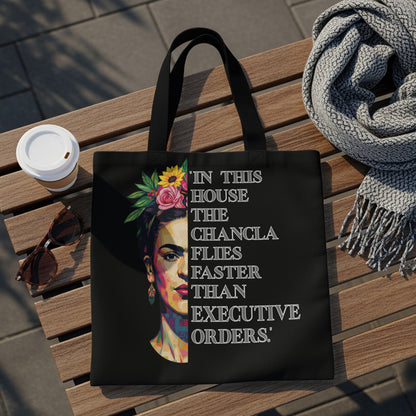 Black tote bag with Frida Kahlo portrait and quote "In this house the changla flies faster than executive orders."
