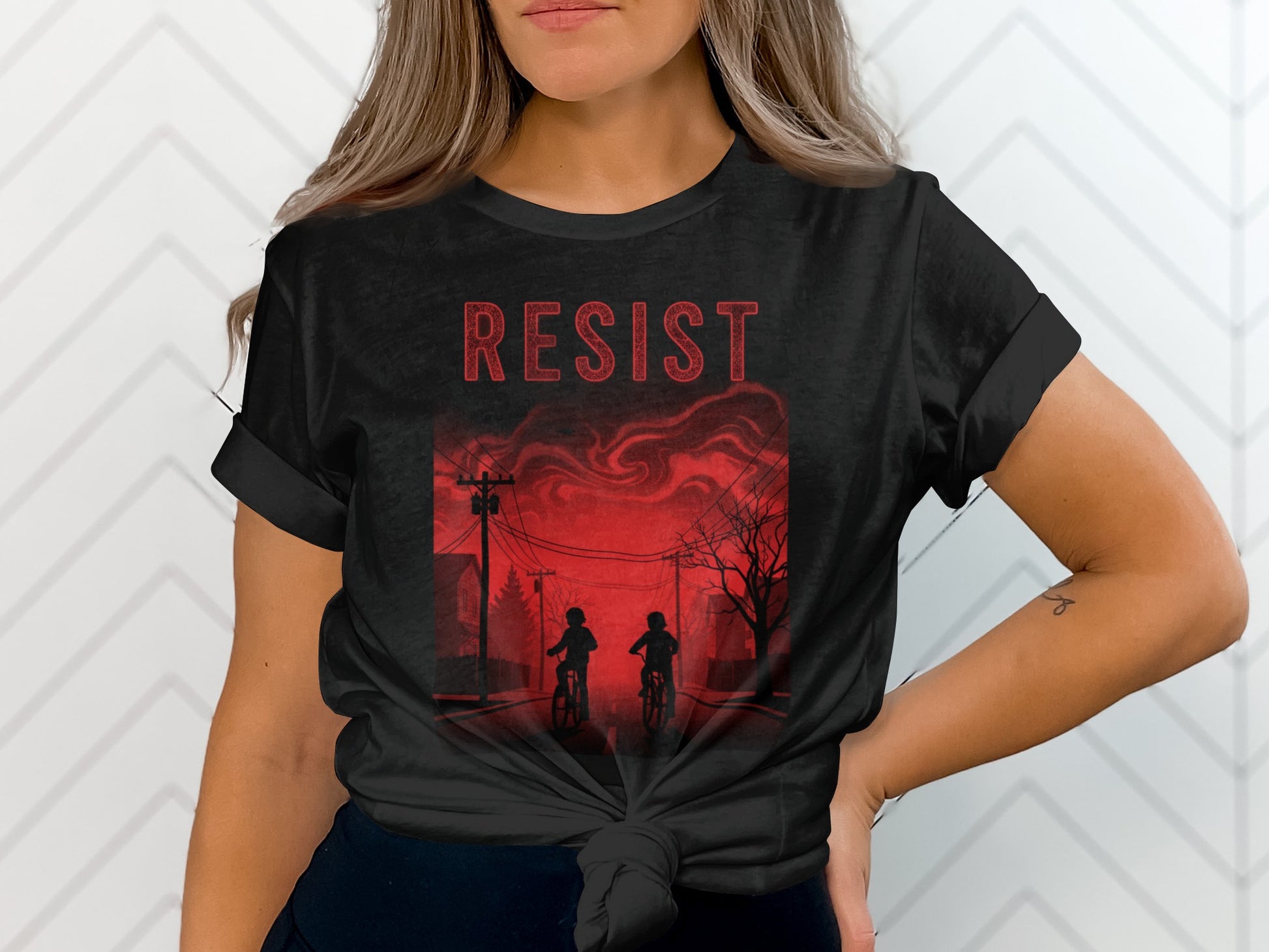 Black t-shirt with red "RESIST" text and silhouetted figures on bicycles.