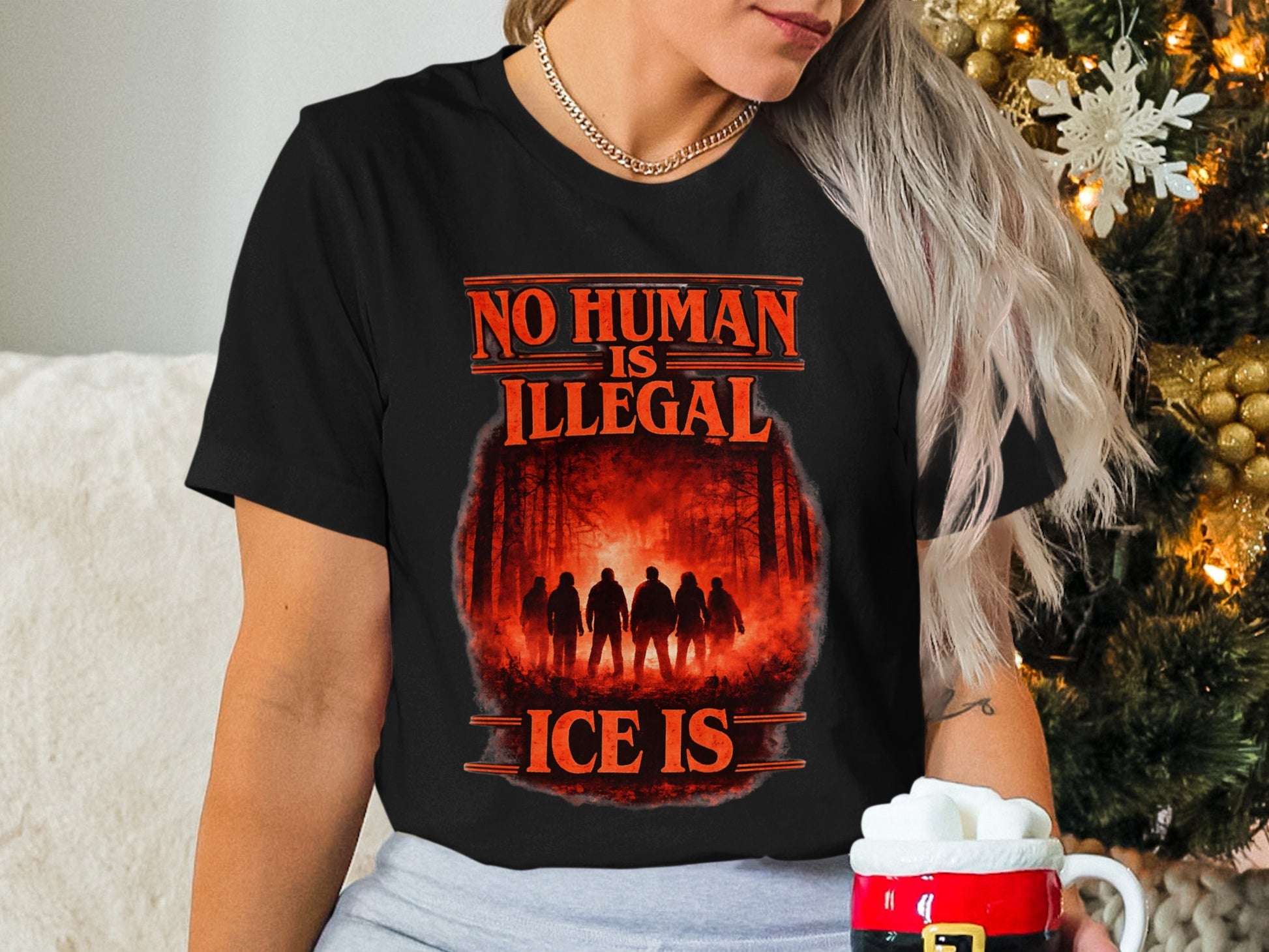 Black t-shirt with "NO HUMAN IS ILLEGAL ICE IS" text and a forest scene.