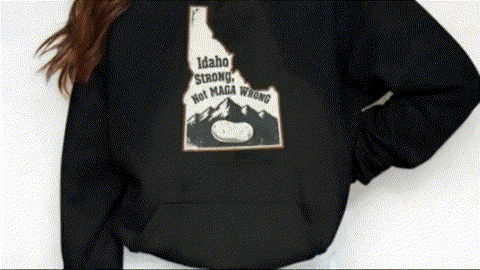 A person wearing a black hoodie with a graphic design on the back.
